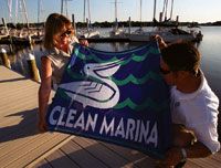 Two people holding up the Clean Marina flag