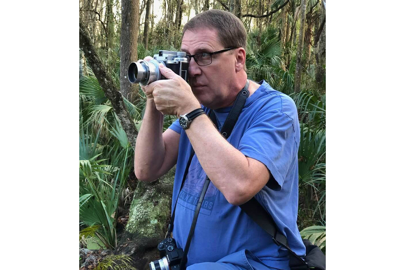 Karl Havens in a blue shirt using a camera