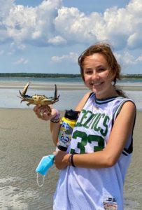 Sophie Maginnes holding a crab on the beach.